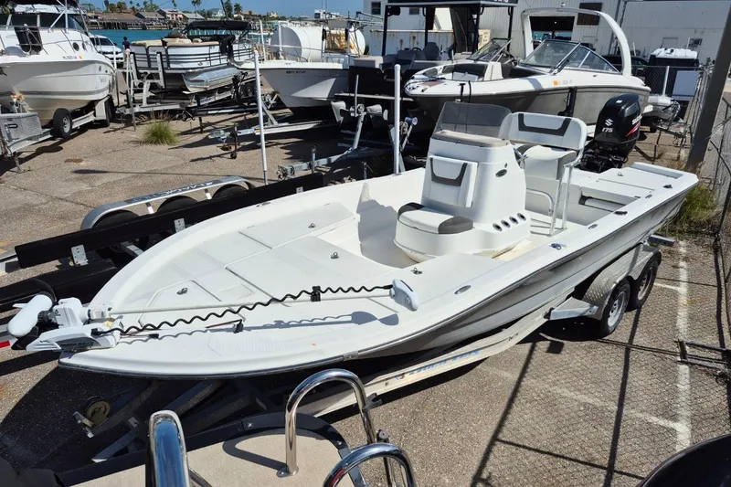 The Image of 2018 Boca Bay 224 Bay boat on trailer, parked in marina with other boats. - 1