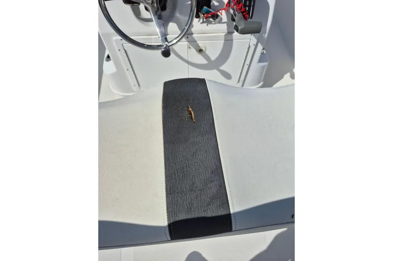 Slide: The Image of 2018 Boca Bay 224 Bay boat seat with visible tear and steering wheel. - 14