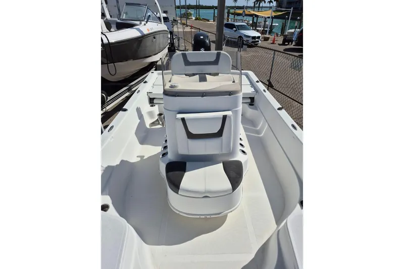 Slide: The Image of 2018 Boca Bay 224 Bay boat interior with seating and console, docked near water. - 23