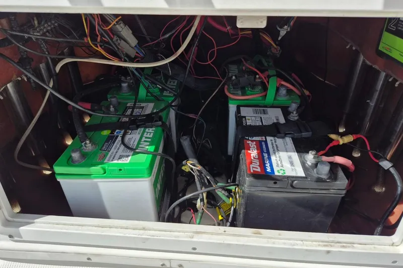 Slide: The Image of 2018 Boca Bay 224 Bay boat battery compartment with multiple marine batteries and wiring. - 24