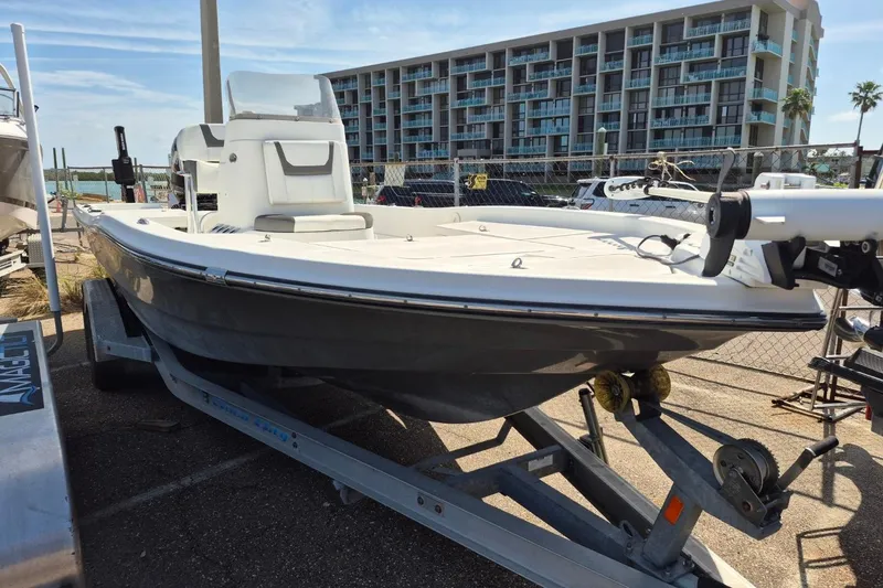 Slide: The Image of 2018 Boca Bay 224 Bay boat on trailer, parked near waterfront buildings. - 4