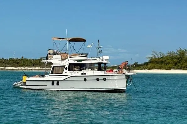The Image of 2024 Ranger Tugs R-29 CB boat anchored in clear blue water near a sandy beach. - 0