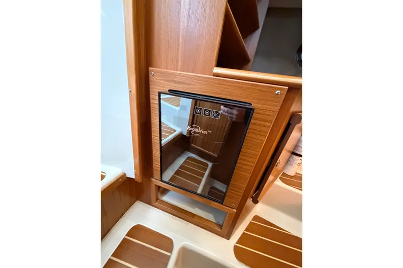 Slide: The Image of 2024 Ranger Tugs R-29 CB interior with compact wooden cabinetry and built-in Koolatron fridge. - 10