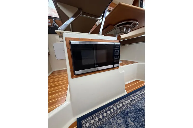 Slide: The Image of 2024 Ranger Tugs R-29 CB interior with built-in microwave and wooden flooring. - 11