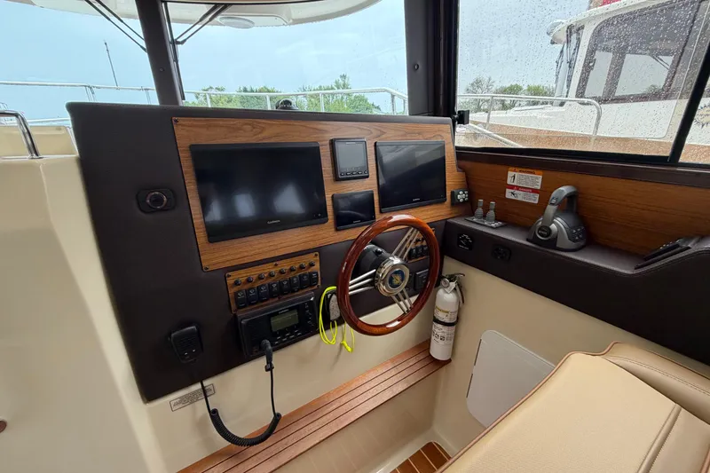 Slide: The Image of 2024 Ranger Tugs R-29 CB helm with modern navigation equipment and wooden accents. - 4