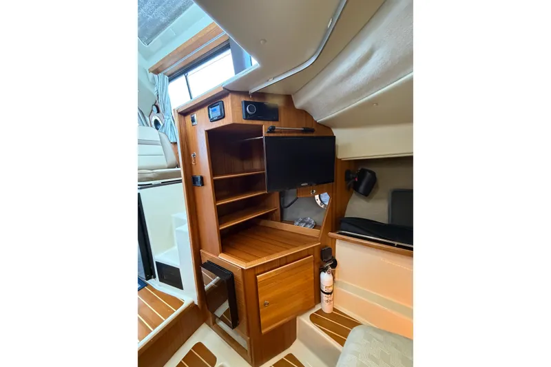 Slide: The Image of 2024 Ranger Tugs R-29 CB interior with wooden cabinetry and mounted TV. - 9