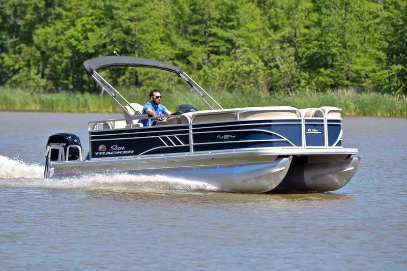 The Image of 2022 Sun Tracker Party Barge 20 DLX cruising on a lake with lush green background. - 1