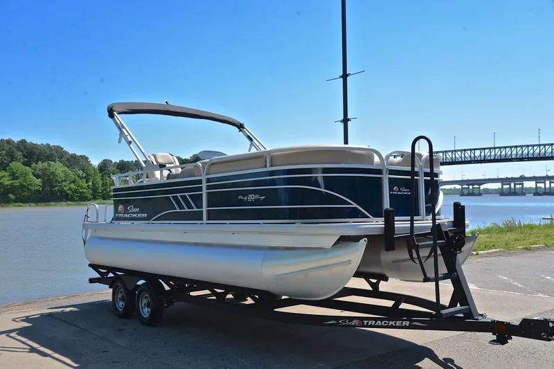 Slide: The Image of 2022 Sun Tracker Party Barge 20 DLX pontoon boat on trailer by a river. - 16