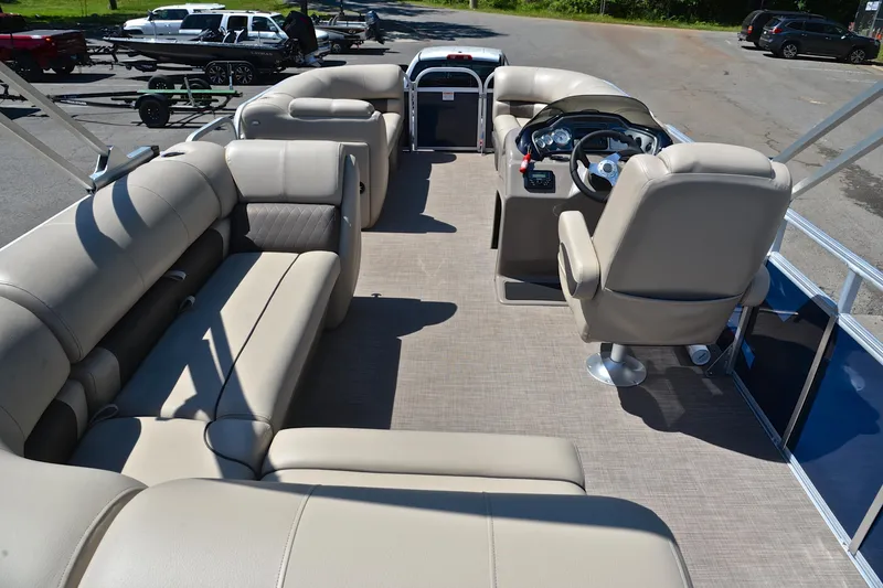 Slide: The Image of 2022 Sun Tracker Party Barge 20 DLX interior with beige seating and steering console. - 18