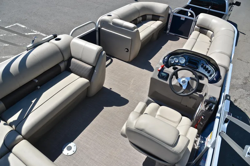 Slide: The Image of 2022 Sun Tracker Party Barge 20 DLX interior with beige seating and steering console. - 19