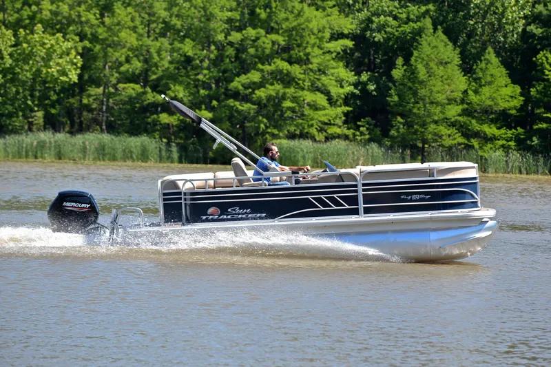 Slide: The Image of 2022 Sun Tracker Party Barge 20 DLX cruising on a lake with lush green trees. - 3