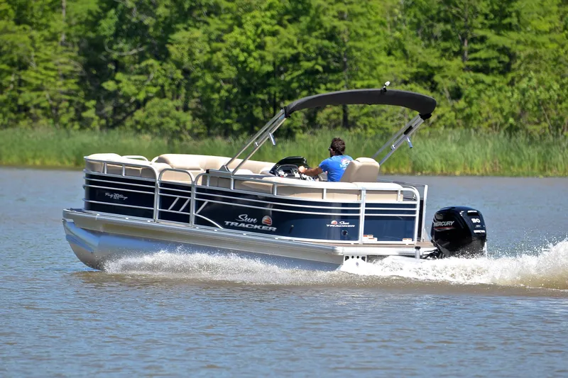 Slide: The Image of 2022 Sun Tracker Party Barge 20 DLX cruising on a lake with lush green background. - 4