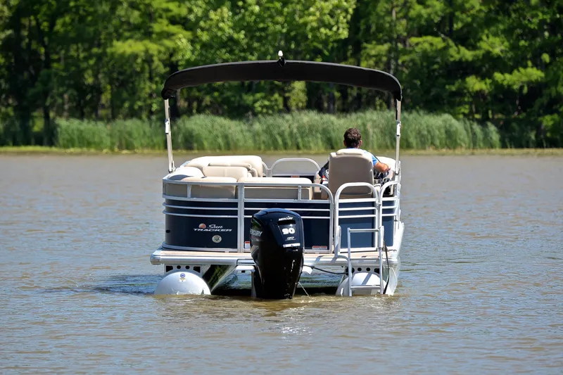 Slide: The Image of 2022 Sun Tracker Party Barge 20 DLX on a serene lake, surrounded by lush greenery. - 7