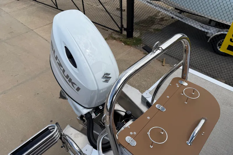 Slide: The Image of 2026 Avalon VENTURE QUAD LOUNGE with Suzuki outboard motor, docked near a fence. - 45