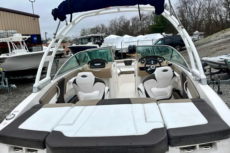 Slide: The Image of 2021 Chaparral 21 SSi OB boat with white and beige interior, parked outdoors. - 11
