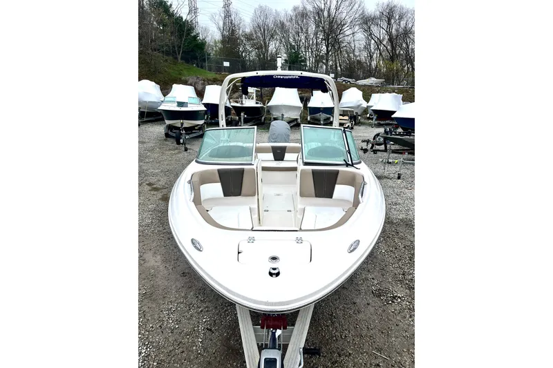 Slide: The Image of 2021 Chaparral 21 SSi OB boat displayed outdoors, surrounded by other covered boats. - 6