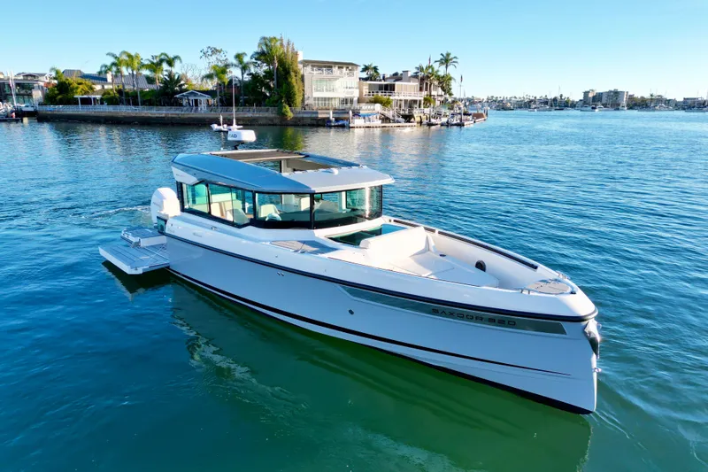 The Image of 2025 Saxdor 320 GTC boat cruising on a sunny, scenic waterfront. - 0