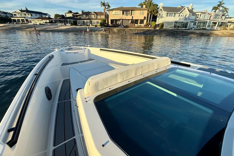 Slide: The Image of 2025 Saxdor 320 GTC boat near waterfront homes, showcasing sleek design and spacious deck. - 12