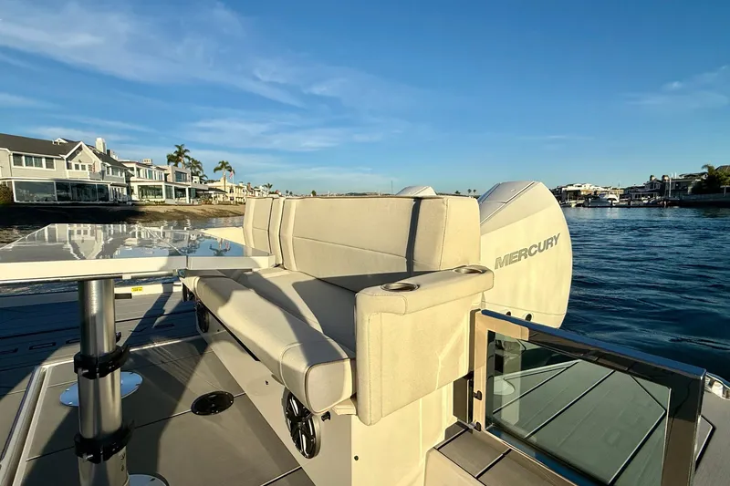 Slide: The Image of 2025 Saxdor 320 GTC boat interior with seating and table, docked near waterfront homes. - 17