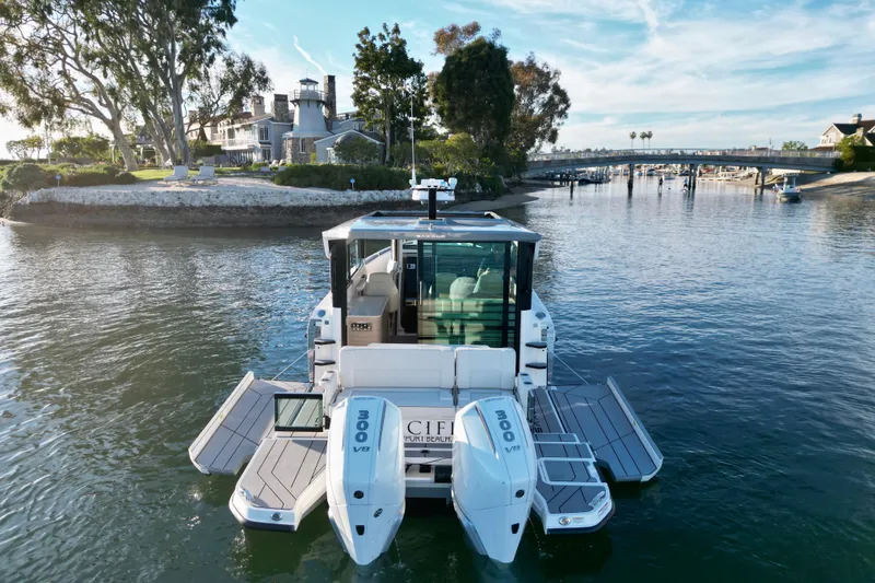 Slide: The Image of Saxdor 320 GTC 2025 boat on serene waterway near luxury homes and bridge. - 2