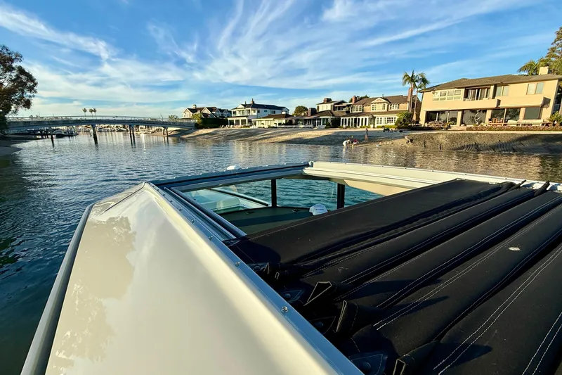 Slide: The Image of 2025 Saxdor 320 GTC boat cruising near waterfront homes under a blue sky. - 21