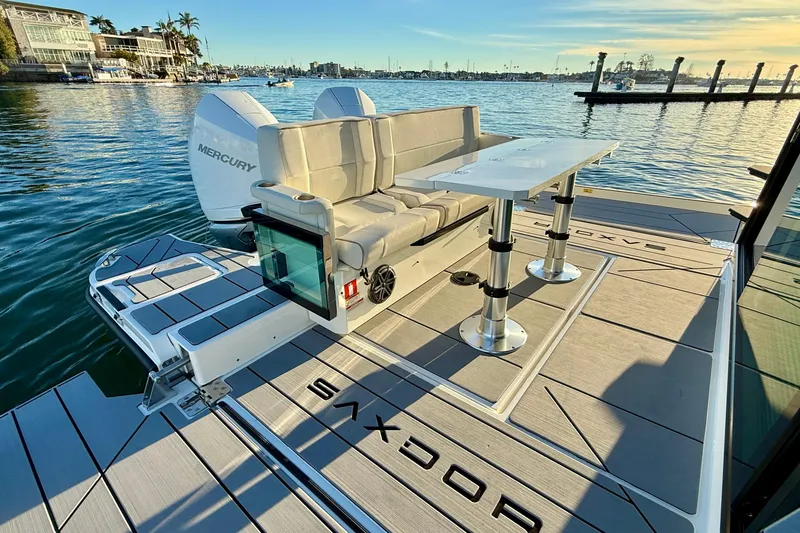 Slide: The Image of 2025 Saxdor 320 GTC boat with seating and table on deck, docked by the water. - 22