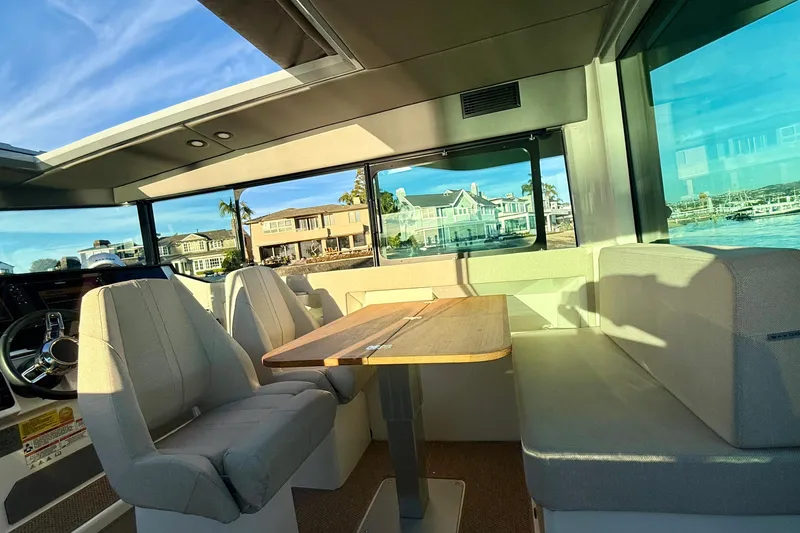 Slide: The Image of Interior of 2025 Saxdor 320 GTC boat with seating and table, showcasing waterfront view. - 25