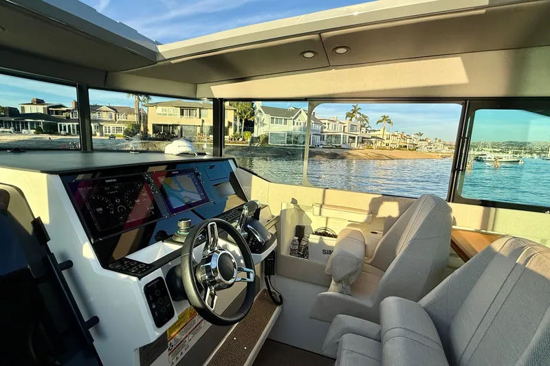 Slide: The Image of Interior view of 2025 Saxdor 320 GTC boat with modern dashboard and waterfront scenery. - 29