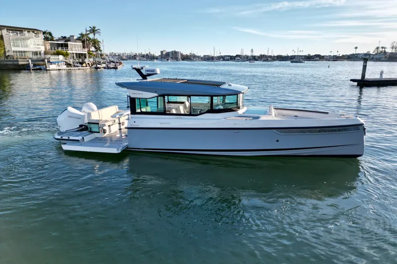 Slide: The Image of 2025 Saxdor 320 GTC boat cruising in a scenic harbor setting. - 3