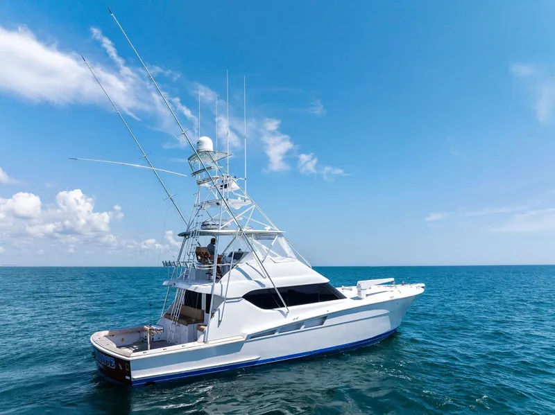 Slide: The Image of 1998 Hatteras 60 Convertible yacht cruising on open sea under clear blue sky. - 4