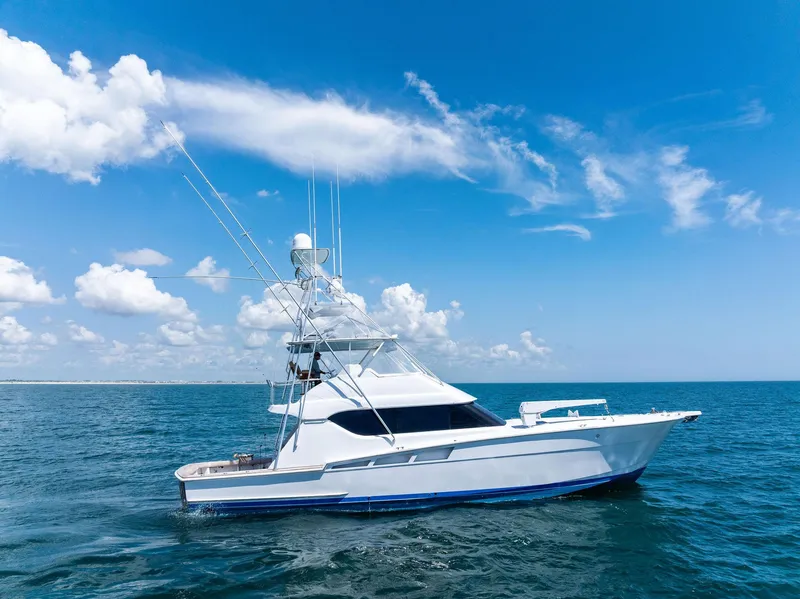 Slide: The Image of 1998 Hatteras 60 Convertible yacht cruising on open sea under clear blue sky. - 5