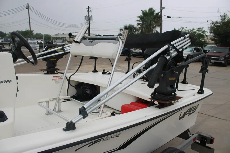 Slide: The Image of 2021 Mako Pro Skiff 17 CC boat with fishing equipment and steering wheel, parked outdoors. - 14