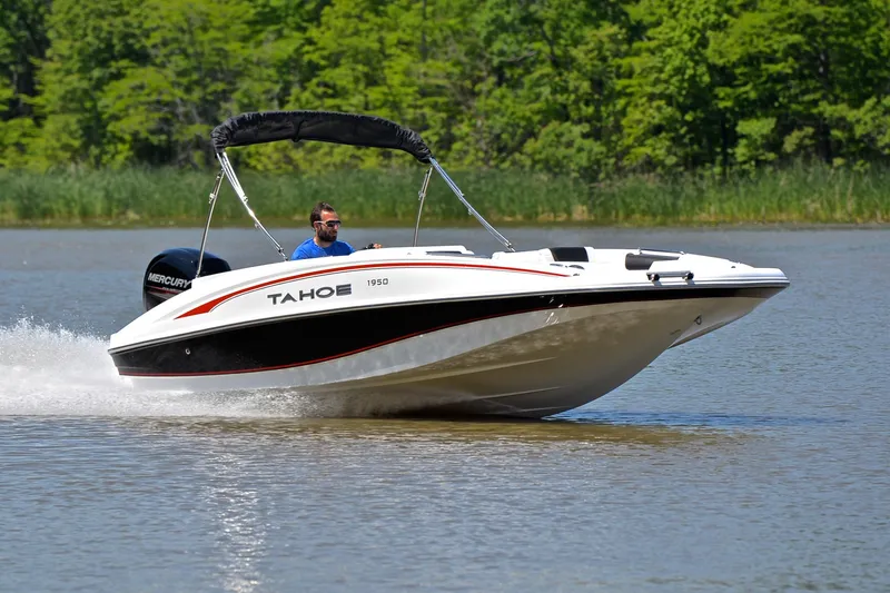 The Image of Tahoe 1950 boat cruising on a lake, 2018 model, with lush green trees in the background. - 1