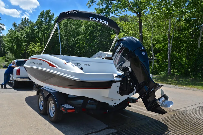 Slide: The Image of 2018 Tahoe 1950 boat on trailer, parked near a forested area. - 12