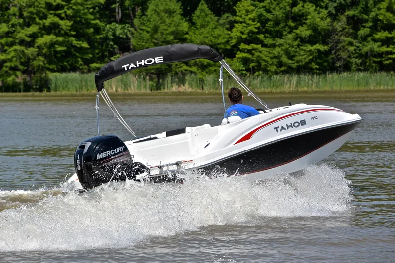 Slide: The Image of A 2018 Tahoe 1950 boat cruising on a lake with lush green trees. - 5