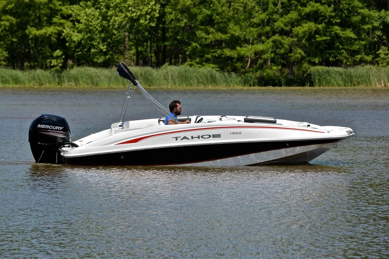 Slide: The Image of A 2018 Tahoe 1950 boat cruising on a calm lake with lush greenery. - 7