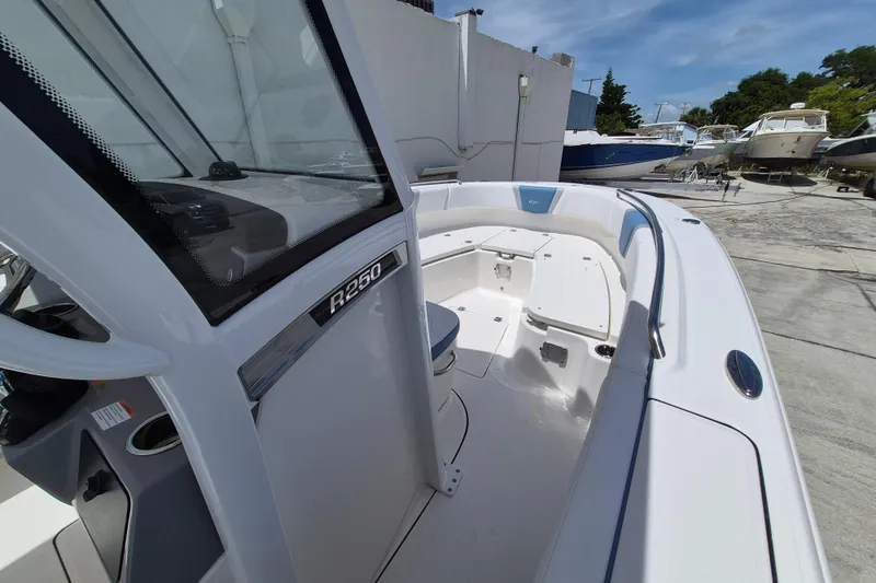 Slide: The Image of 2026 Robalo R250 Center Console boat, sleek design, docked outdoors under clear sky. - 8