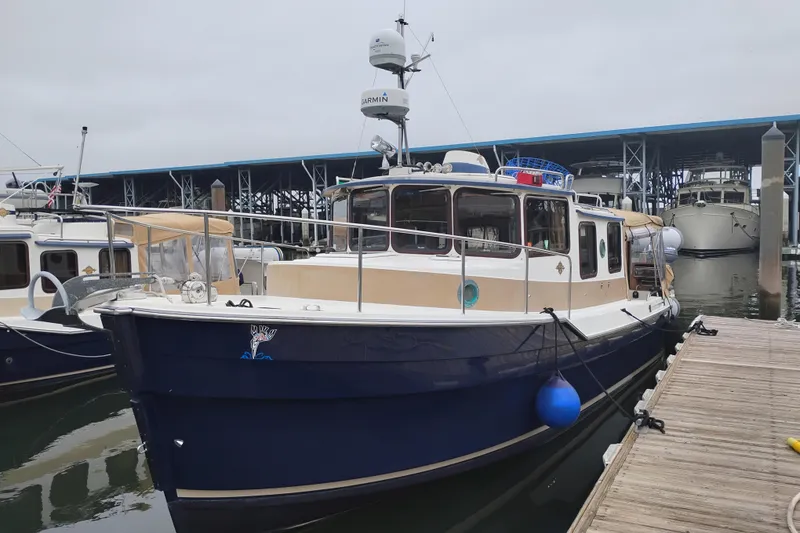 The Image of 2014 Ranger Tugs R-29 docked at marina, featuring blue hull and beige accents. - 0
