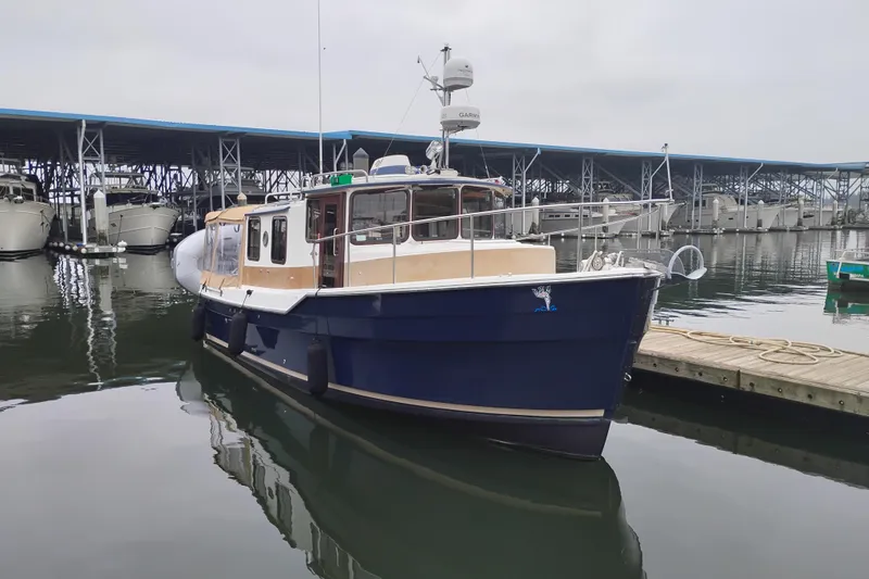 Slide: The Image of 2014 Ranger Tugs R-29 boat docked in a marina, featuring a blue hull. - 1