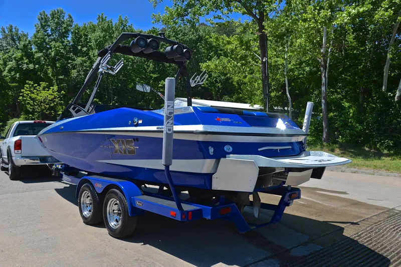 Slide: The Image of 2014 Axis A22 blue boat on trailer, parked near trees. - 12