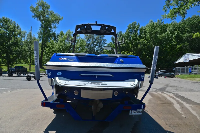 Slide: The Image of 2014 Axis A22 boat, blue, parked on a sunny day with trees in the background. - 13