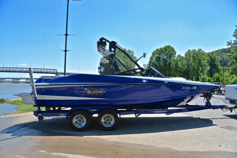 Slide: The Image of 2014 Axis A22 boat on trailer by riverside, sunny day, lush greenery background. - 15