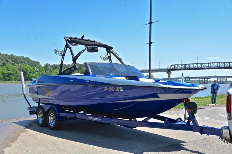 Slide: The Image of 2014 Axis A22 boat on trailer by riverside, under clear blue sky. - 16
