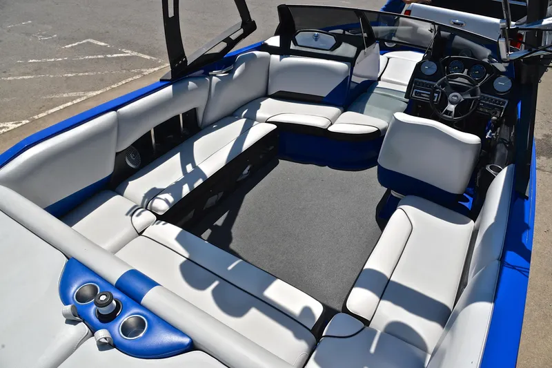 Slide: The Image of 2014 Axis A22 boat interior with white and blue seating, steering console, and cup holders. - 19