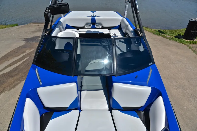 Slide: The Image of 2014 Axis A22 boat with blue and white interior, parked near a lake. - 20