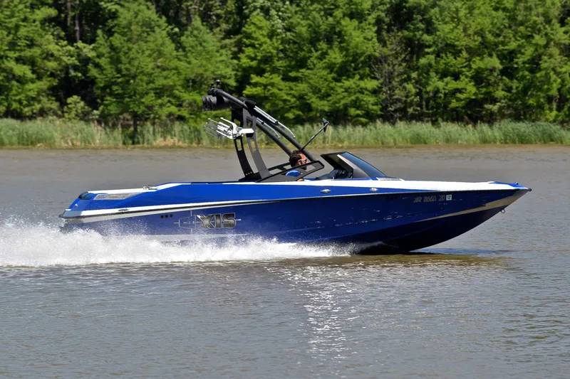 Slide: The Image of 2014 Axis A22 boat speeding on a lake with lush green trees in the background. - 3