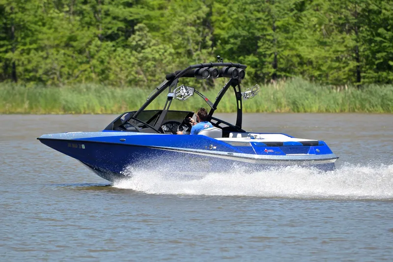 Slide: The Image of 2014 Axis A22 boat speeding on a lake with lush green background. - 4