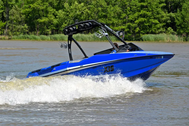 Slide: The Image of Blue 2014 Axis A22 boat cruising on a lake with lush green trees. - 5