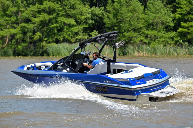 Slide: The Image of 2014 Axis A22 boat cruising on a lake with lush green trees in the background. - 6