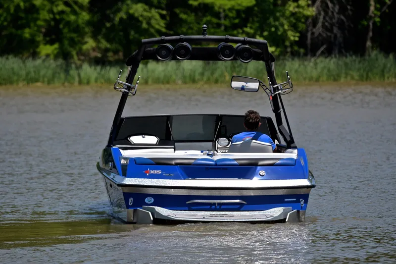 Slide: The Image of 2014 Axis A22 boat cruising on a calm lake with lush green background. - 8